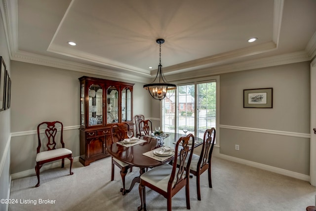 dining space featuring a notable chandelier, a raised ceiling, light colored carpet, and crown molding