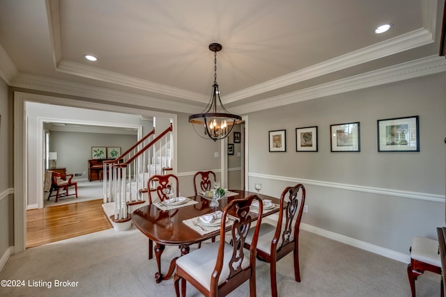 dining space with a tray ceiling, light colored carpet, and a notable chandelier