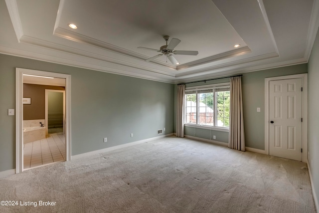 empty room with light colored carpet, a raised ceiling, ceiling fan, and ornamental molding