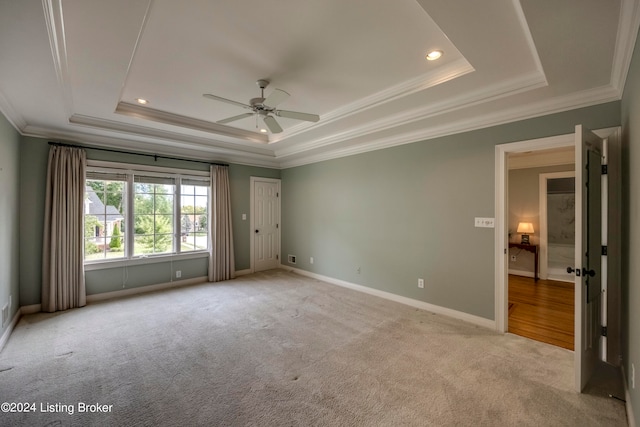 spare room with ceiling fan, crown molding, light carpet, and a tray ceiling