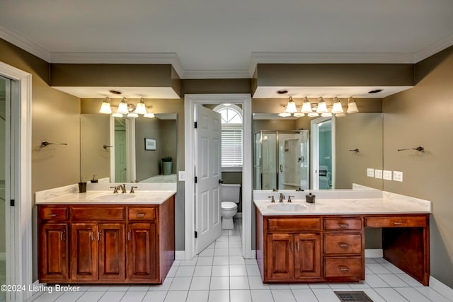 bathroom featuring tile patterned floors, toilet, vanity, a shower with shower door, and ornamental molding