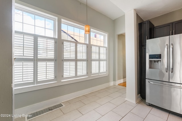 kitchen featuring light tile patterned flooring, dark brown cabinetry, stainless steel fridge with ice dispenser, and hanging light fixtures