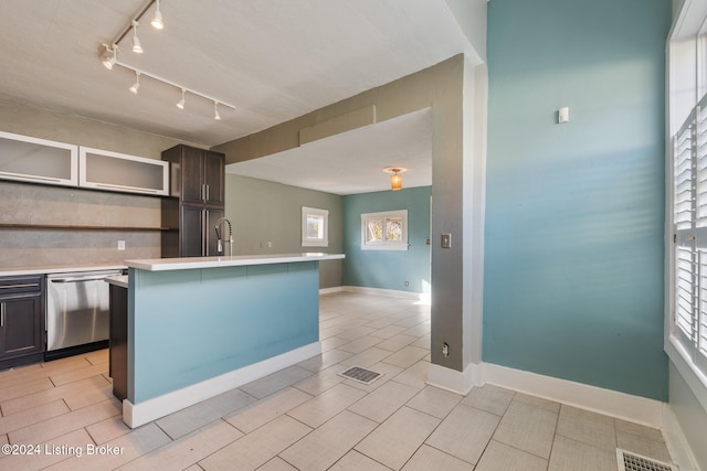 kitchen featuring a kitchen breakfast bar, rail lighting, stainless steel dishwasher, dark brown cabinetry, and a kitchen island with sink