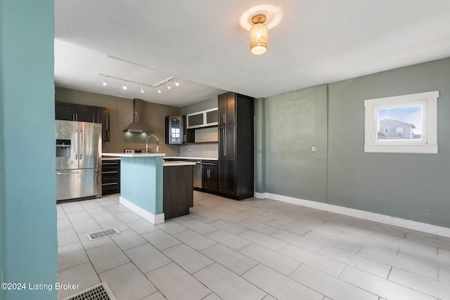 kitchen with wall chimney exhaust hood, dark brown cabinetry, stainless steel refrigerator with ice dispenser, and a kitchen island with sink