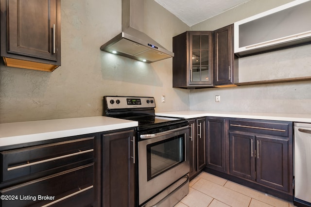 kitchen with dark brown cabinets, stainless steel appliances, light tile patterned floors, and wall chimney exhaust hood