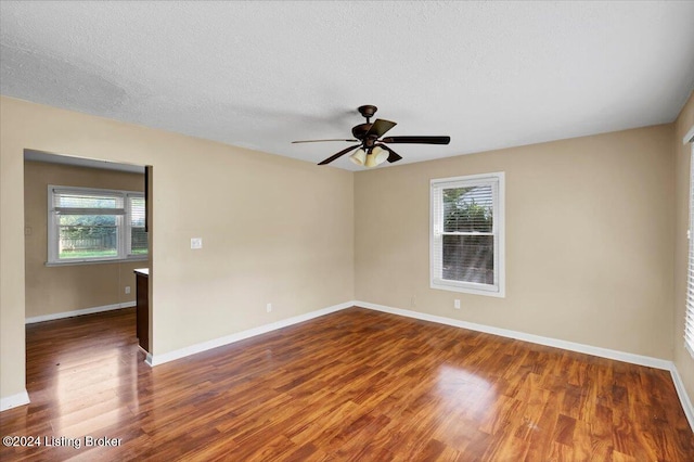 empty room with a textured ceiling, ceiling fan, and dark wood-type flooring