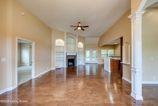 unfurnished living room with ornate columns, ceiling fan, sink, hardwood / wood-style flooring, and built in features