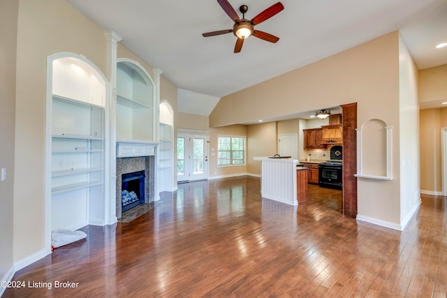 unfurnished living room featuring a high end fireplace, ceiling fan, built in features, dark hardwood / wood-style floors, and lofted ceiling