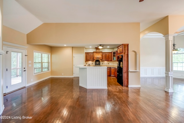 kitchen featuring black refrigerator, decorative columns, a kitchen island, and a healthy amount of sunlight