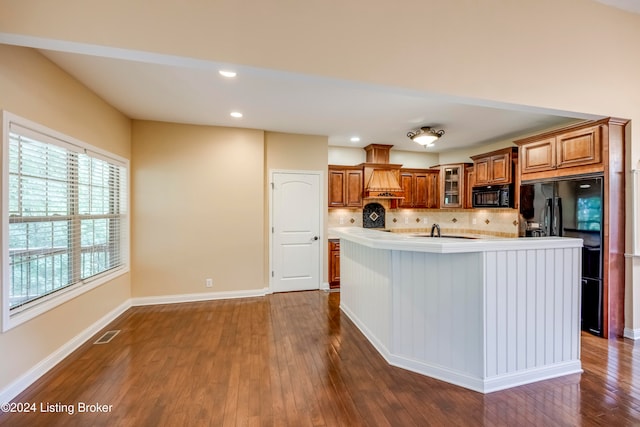 kitchen featuring a kitchen island with sink, dark wood-type flooring, and black appliances