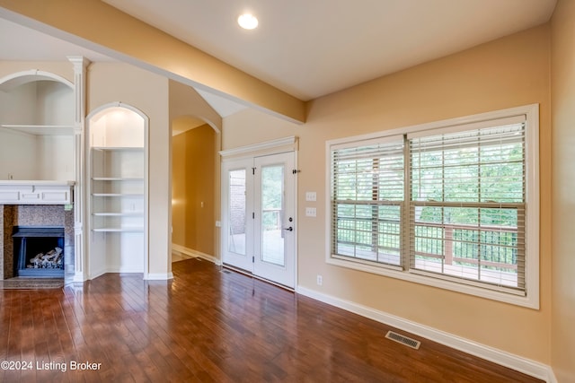 unfurnished living room featuring dark hardwood / wood-style flooring and a tile fireplace