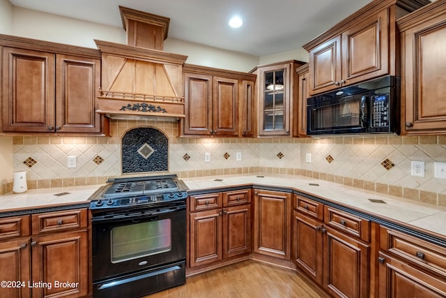 kitchen with black appliances, light hardwood / wood-style flooring, and tasteful backsplash