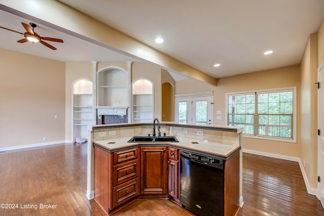 kitchen with ceiling fan, sink, a center island with sink, black dishwasher, and light hardwood / wood-style floors