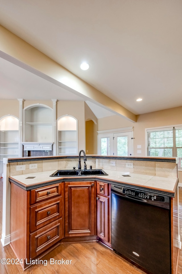 kitchen featuring a wealth of natural light, sink, black dishwasher, light hardwood / wood-style flooring, and a kitchen island with sink