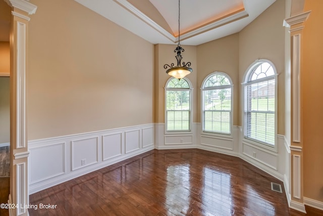 unfurnished room featuring ornamental molding, decorative columns, a raised ceiling, and dark wood-type flooring