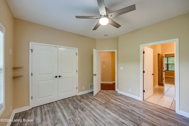 unfurnished bedroom with a closet, light hardwood / wood-style floors, and ceiling fan