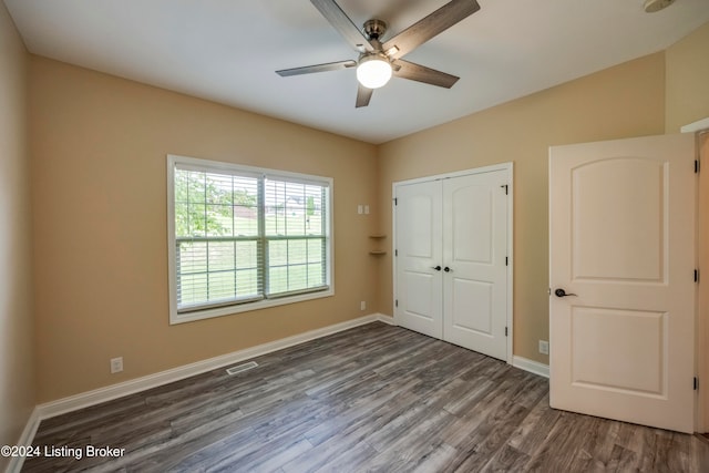 unfurnished bedroom featuring dark hardwood / wood-style floors, ceiling fan, and a closet