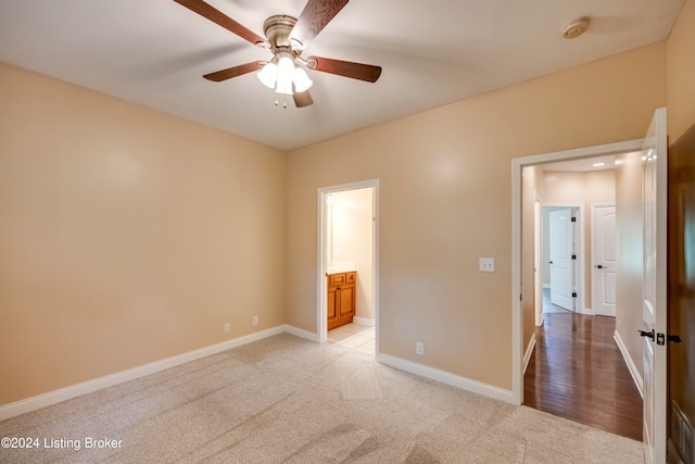 unfurnished bedroom featuring connected bathroom, light colored carpet, and ceiling fan