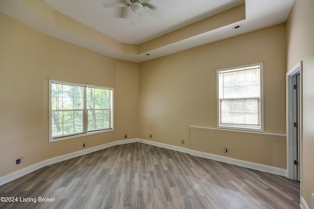 spare room with ceiling fan, light hardwood / wood-style floors, and a tray ceiling