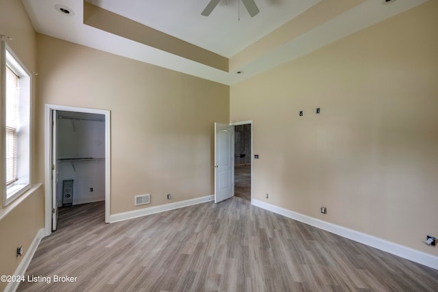 spare room with ceiling fan, a healthy amount of sunlight, a towering ceiling, and light hardwood / wood-style flooring