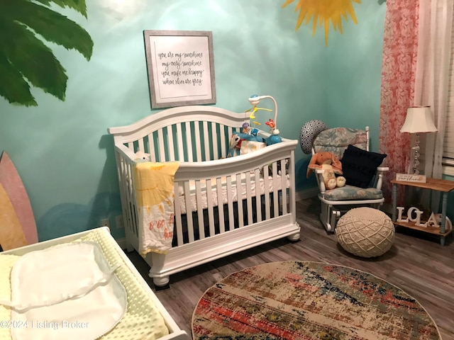 bedroom featuring dark wood-type flooring and a nursery area