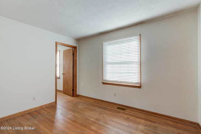 unfurnished room featuring a textured ceiling and light hardwood / wood-style flooring