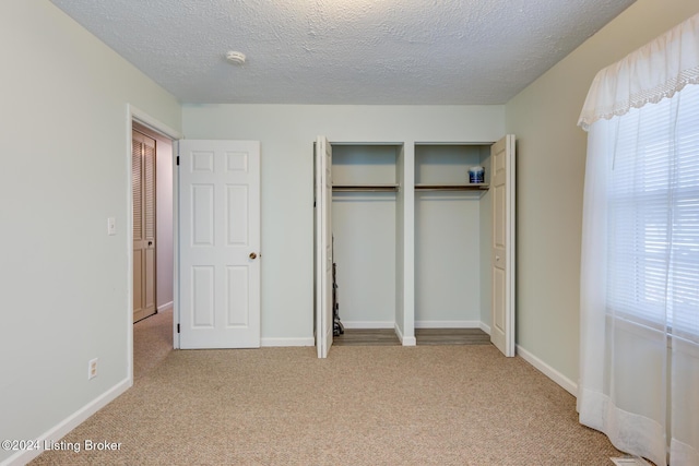 unfurnished bedroom featuring a textured ceiling and light carpet