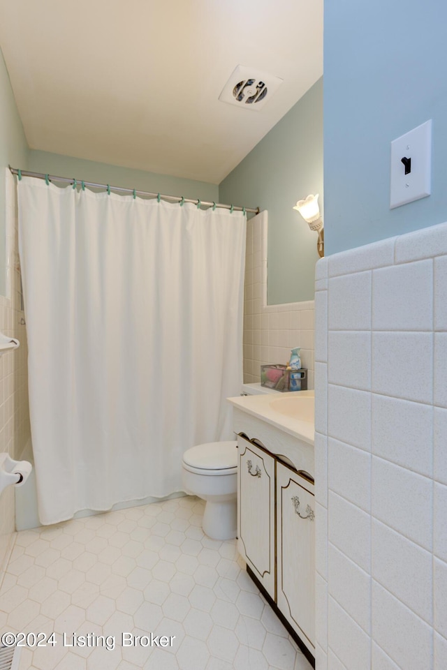 bathroom featuring tile patterned flooring, vanity, tile walls, and toilet