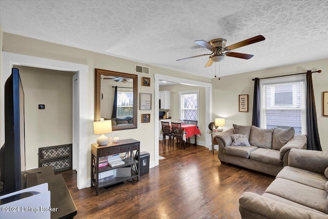 living room with dark hardwood / wood-style flooring, a healthy amount of sunlight, and a textured ceiling