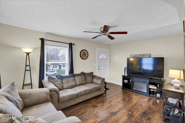 living room with ceiling fan, dark wood-type flooring, and a textured ceiling