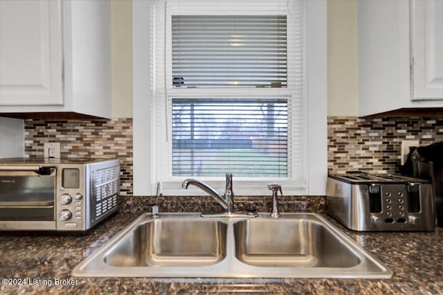 kitchen featuring tasteful backsplash, white cabinetry, and sink