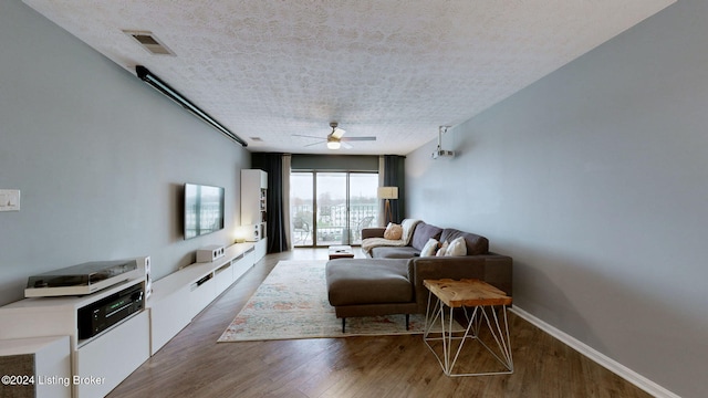 living room featuring ceiling fan, wood-type flooring, and a textured ceiling