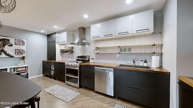 kitchen featuring white cabinetry, sink, wall chimney exhaust hood, wooden counters, and appliances with stainless steel finishes