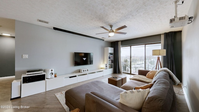 living room with hardwood / wood-style flooring, ceiling fan, and a textured ceiling