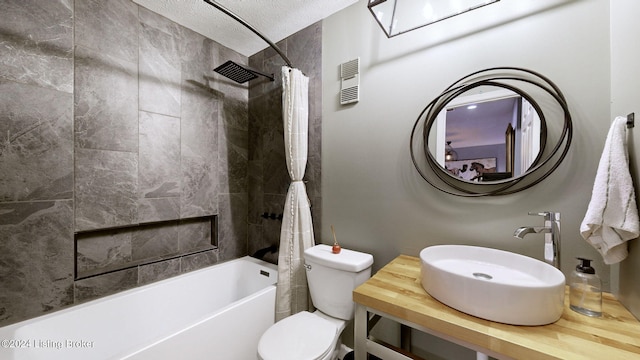 full bathroom with sink, shower / bath combination with curtain, a textured ceiling, and toilet