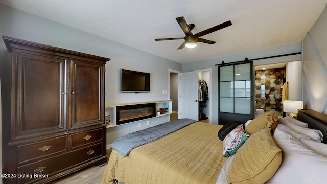 bedroom featuring ceiling fan, ensuite bathroom, light hardwood / wood-style floors, a walk in closet, and a closet