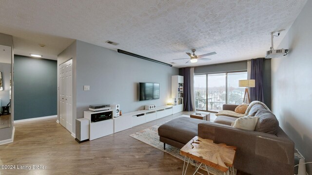 living room with ceiling fan, light hardwood / wood-style floors, and a textured ceiling