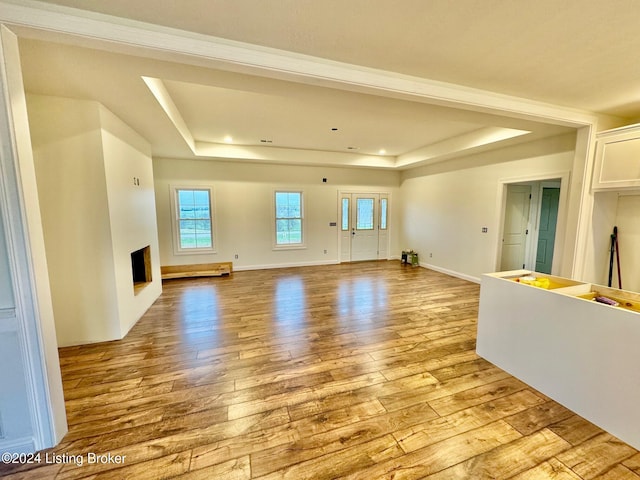 unfurnished living room featuring a tray ceiling and light hardwood / wood-style flooring