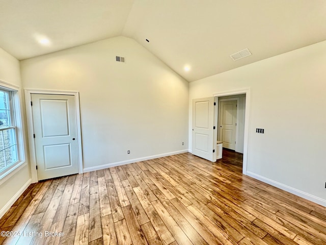 spare room with light hardwood / wood-style flooring and lofted ceiling