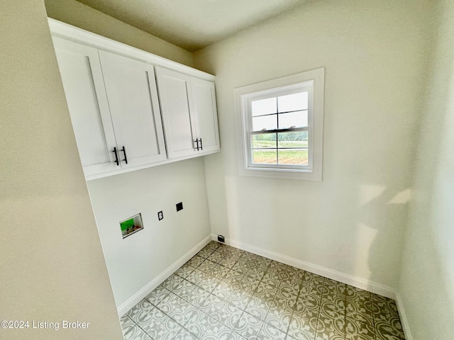 clothes washing area featuring electric dryer hookup, hookup for a washing machine, light tile patterned flooring, and cabinets