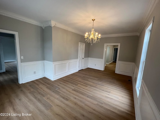 unfurnished dining area featuring a chandelier, hardwood / wood-style flooring, and crown molding