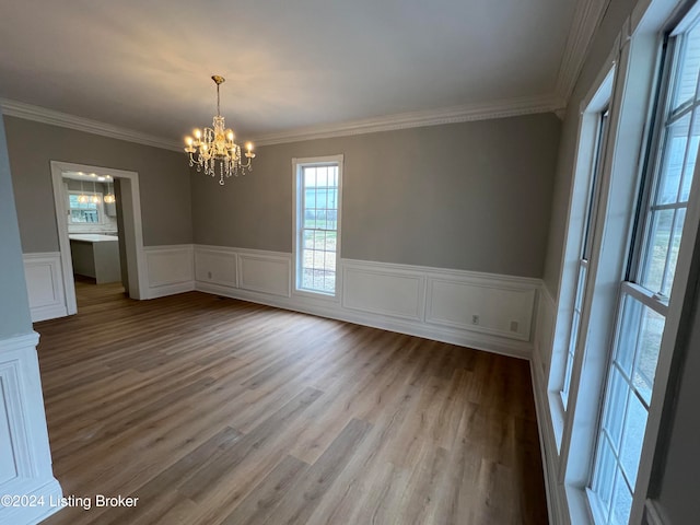 unfurnished dining area with a notable chandelier, light wood-type flooring, and ornamental molding