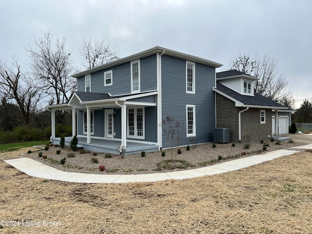 exterior space with covered porch, a garage, and cooling unit