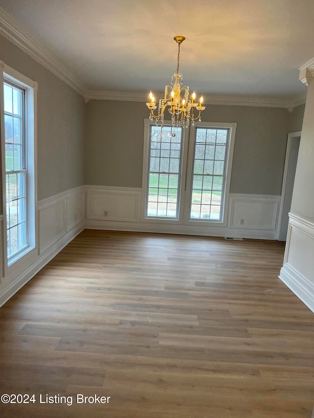 unfurnished dining area featuring an inviting chandelier, a healthy amount of sunlight, and crown molding