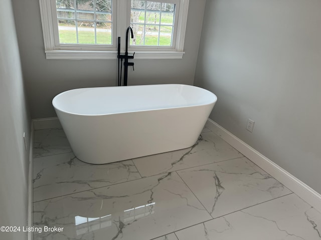 bathroom with a tub to relax in and plenty of natural light