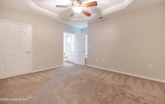 carpeted spare room featuring a tray ceiling, crown molding, ceiling fan, and a textured ceiling