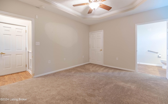 spare room featuring a raised ceiling, crown molding, ceiling fan, and light carpet