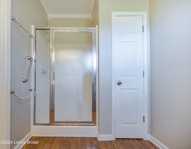 bathroom featuring wood-type flooring, crown molding, and a shower with shower door