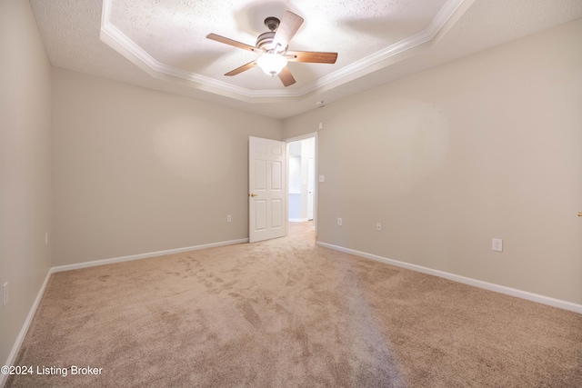 empty room with ceiling fan, crown molding, a textured ceiling, a tray ceiling, and carpet