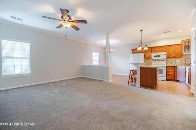 kitchen with decorative columns, ornamental molding, white appliances, decorative light fixtures, and a kitchen island